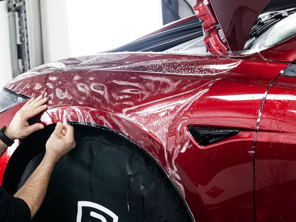 Nakładanie folii PPF na błotnik Tesla Model 3 w profesjonalnym studiu detailingu.